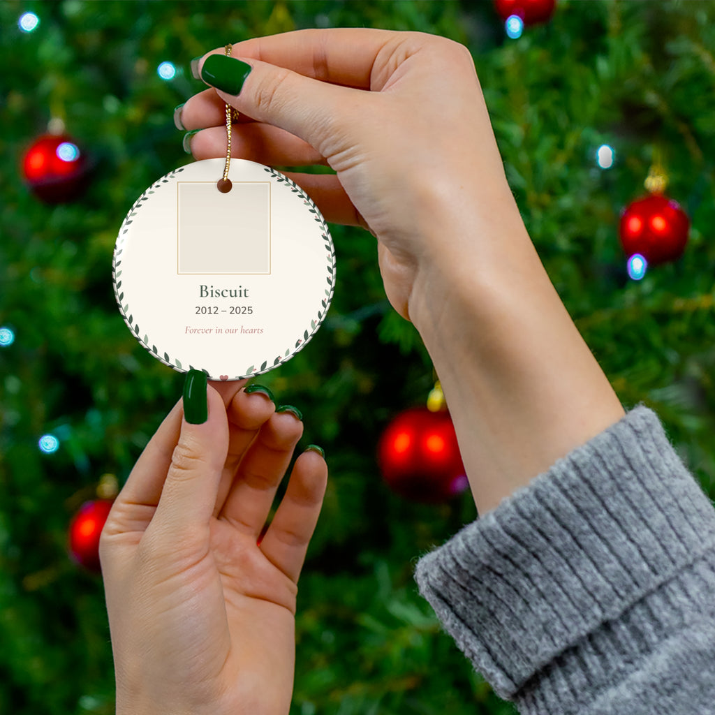 Round ceramic personalized pet memorial ornament with a pet photo, name and dates in a leafy wreath, 'Forever in our hearts' - view 3