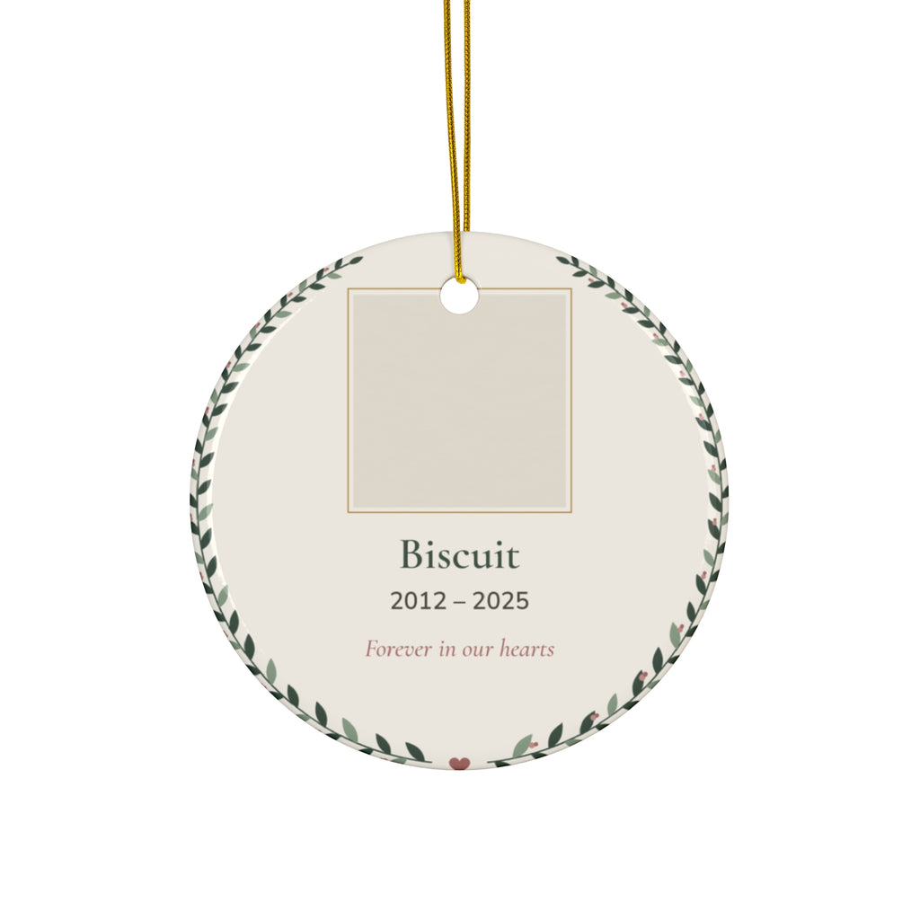 Round ceramic personalized pet memorial ornament with a pet photo, name and dates in a leafy wreath, 'Forever in our hearts'
