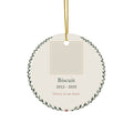 Round ceramic personalized pet memorial ornament with a pet photo, name and dates in a leafy wreath, 'Forever in our hearts'