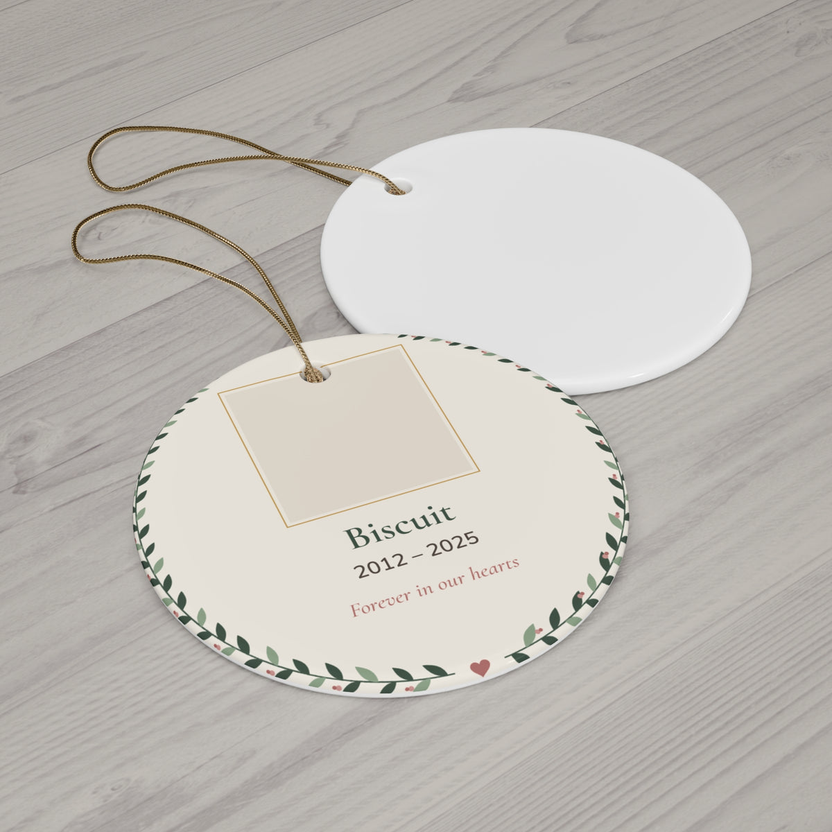 Round ceramic personalized pet memorial ornament with a pet photo, name and dates in a leafy wreath, 'Forever in our hearts' - view 2